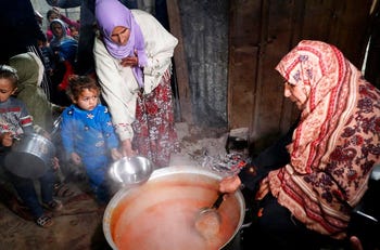 La donna palestinese Samera Abu Amra distribuisce pasti gratuiti di stufato di piselli per i poveri residenti a Gaza City, l'anno scorso.