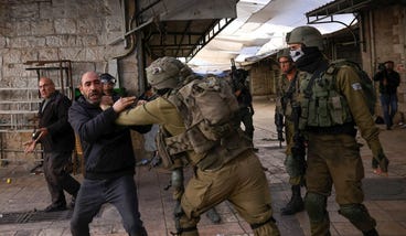 Israeli security forces hold back a Palestinian man in the occupied West Bank city of Hebron, in November., Credit: HAZEM BADER - AFP Israeli security forces hold back a Palestinian man in the occupied West Bank city of Hebron, in November.