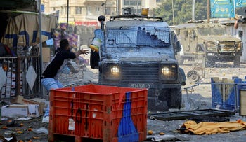 Un palestinese lancia un secchio di vernice contro un veicolo militare israeliano durante un raid a Nablus, mercoledì.