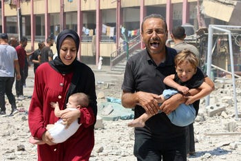 Los palestinos cargan a sus hijos mientras huyen después de un ataque israelí contra una escuela, que alberga a palestinos desplazados, en el centro de la ciudad de Gaza el martes.
