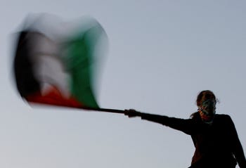 Un manifestante ondea una bandera palestina mientras está sentado en lo alto de una valla en Union Park, durante una protesta en apoyo a los palestinos en Gaza, al margen de la Convención Nacional Demócrata, en Chicago el jueves.