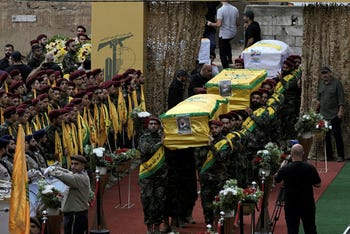 Combatientes de Hezbollah cargan el ataúd de cuatro camaradas caídos que murieron el lunes después de que explotaran sus buscapersonas de mano, en el suburbio sureño de Beirut, Líbano, el miércoles 18 de septiembre de 2024. (AP Foto/Bilal Hussein)