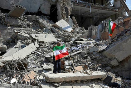 Un hombre sostiene una bandera iraní entre los escombros de un edificio destruido tras los ataques aéreos en el centro de Teherán el miércoles.