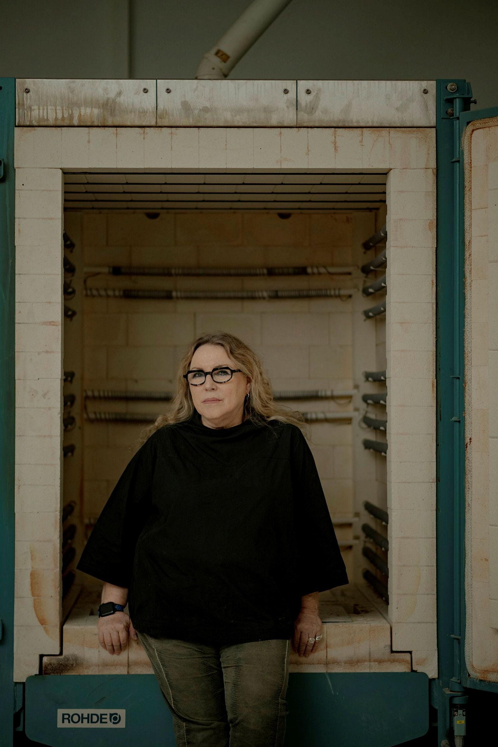 Yael Atzmoni in front of a ceramic firing kiln.