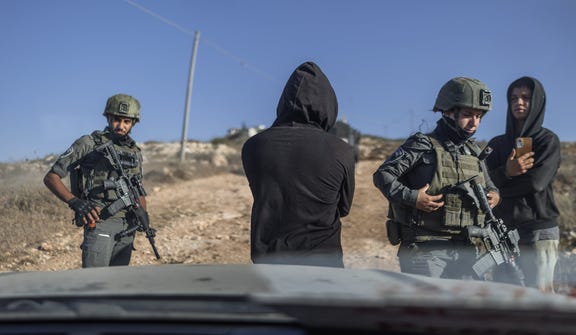 Israeli soldiers surrounding a car near the besieged Palestinian homes in Qusra, West Bank, on Monday.
