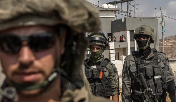 Israeli soldiers standing in front of a home where three Palestinian families are besieged in Qusra, northern West Bank, on Friday.