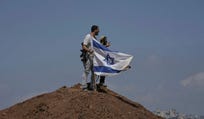 Settlers put up an Israeli flag on a hilltop after it was taken down by Israeli and foreign peace activists on the outskirts of the West Bank city of Beit Sahour, Friday