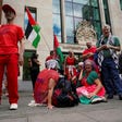Demonstrators sit outside the Westminster Magistrates Court in London in July, as a plea hearing for 25 people accused of showing support for Palestine Action takes place.
