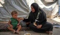 A Palestinian woman feeds a child a meal cooked using combustible materials collected from a garbage dump amid a shortage of cooking gas in Deir al-Balah, central Gaza Strip, Saturday, Aug. 22, 2026. (AP Photo/Abdel Kareem Hana)