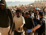 Migrants are escorted from a makeshift beach camp to official shelters across the city after authorities cleared the site, following a mass crossing from Morocco, in Spain's North African enclave of Ceuta, two weeks ago. Credit: Violeta Santos Moura/REUTERS Migrants are escorted from a makeshift beach camp to official shelters across the city after authorities cleared the site, following a mass crossing from Morocco, in Spain's North African enclave of Ceuta, two weeks ago.