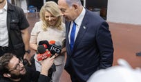 Yonatan Urich, bottom left, holds microphones as Prime Minister Benjamin Netanyahu and his wife Sara address reporters in Tel Aviv, 2022.