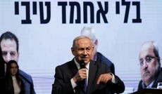 Benjamin Netanyahu at a Likud election conference, 2020. A screen behind him reads, "Without Ahmad Tibi."