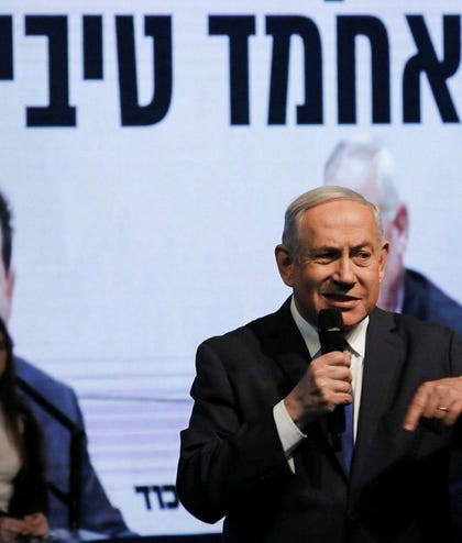 Benjamin Netanyahu at a Likud election conference, 2020. A screen behind him reads, "Without Ahmad Tibi."