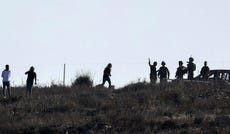 Israeli settlers and soldiers gather near an olive grove before a reported attack against Palestinians picking olives in the village of Beita, south of Nablus, in the occupied West Bank on October 2, 2026.