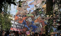 People march past the 'Cable Street' mural in Whitechapel, east London, on October 4, marking the 90th anniversary of the Battle of Cable Street.