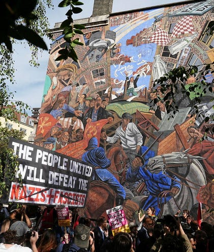 People march past the 'Cable Street' mural in Whitechapel, east London, on October 4, marking the 90th anniversary of the Battle of Cable Street.