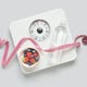 Weight scales with measuring tape, bottle of water and fresh berries on grey background. Slimming concept