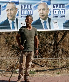 A Palestinian farmer stands next to an election banner featuring Israel's Prime Minister Benjamin Netanyahu near the Palestinian-owned olive groves in the village of Rantes near Ramallah, in the West Bank on October 6, 2026.